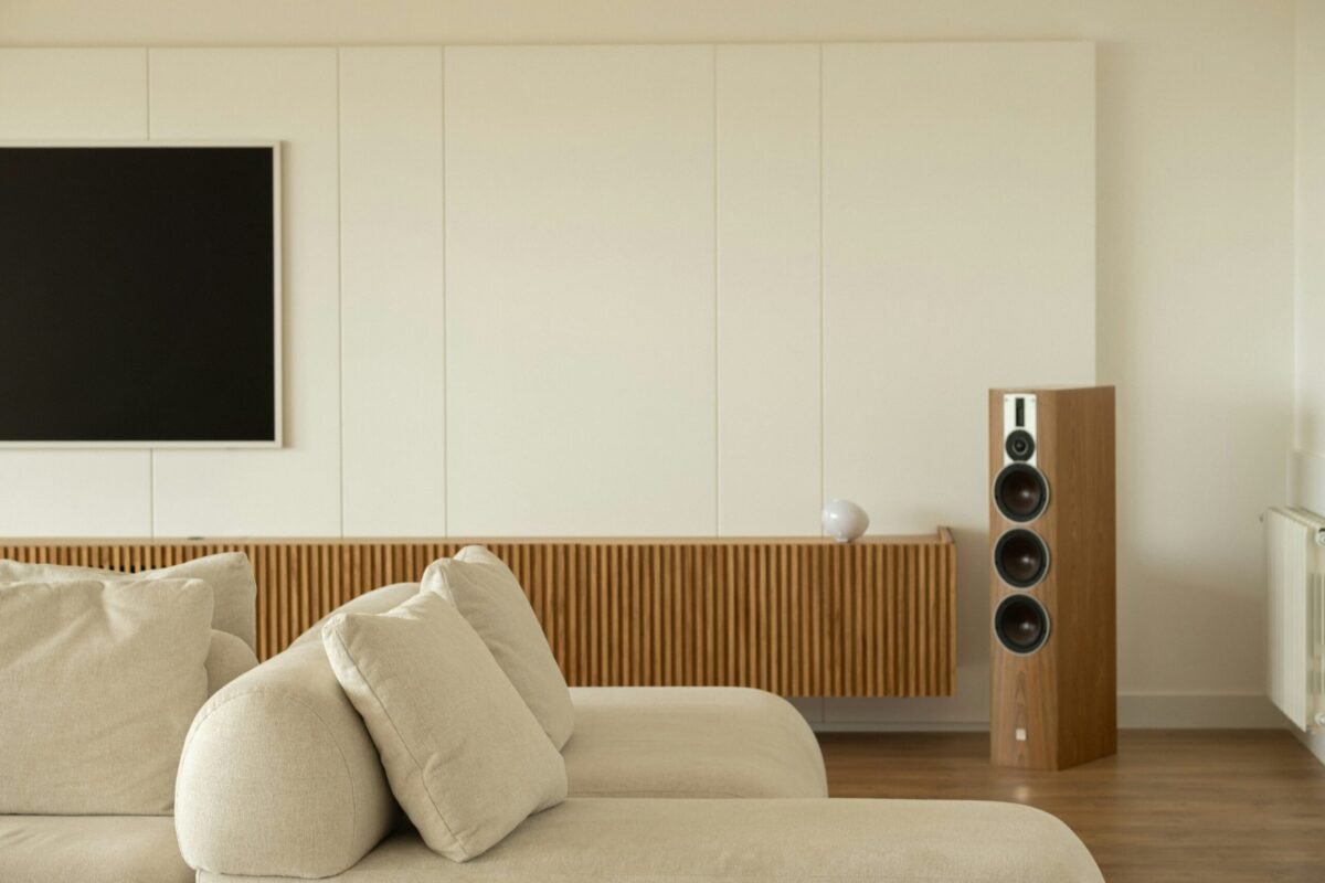Wireless soundbar below TV with rear surround speakers on stands, no visible audio cables in minimalist living room