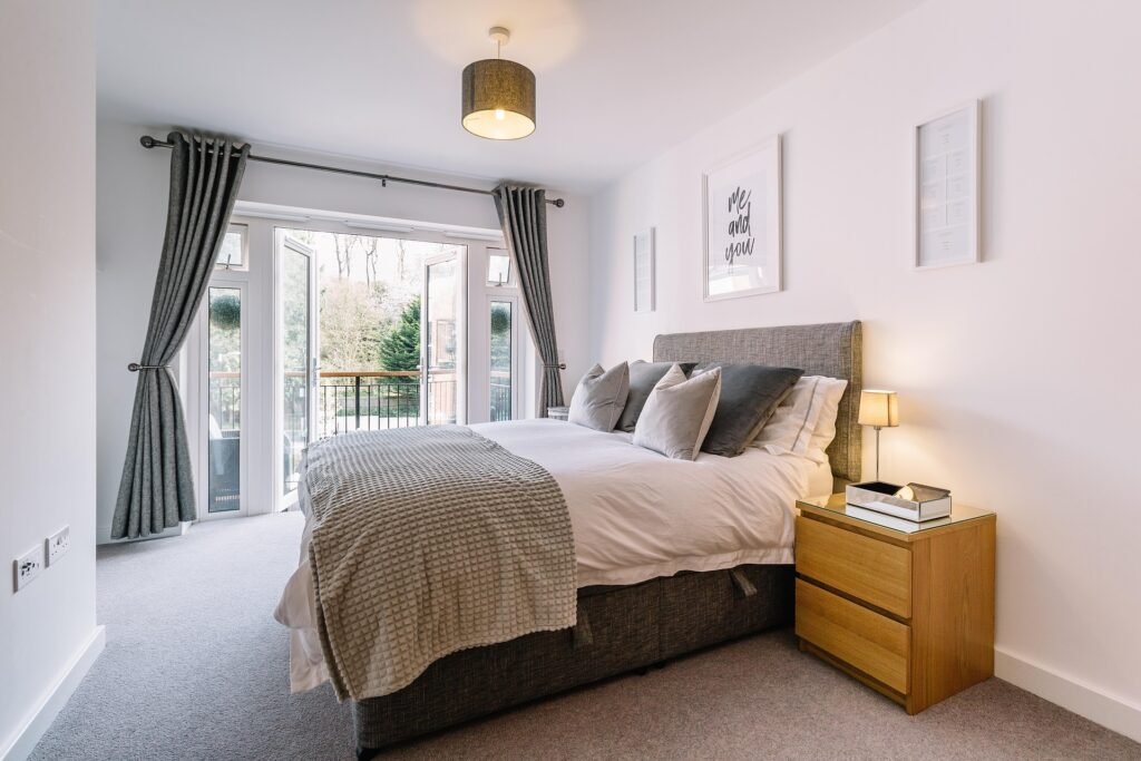 Cozy bedroom with warm sunrise-style lighting from smart bulbs, smart speaker on nightstand, and neatly made bed
