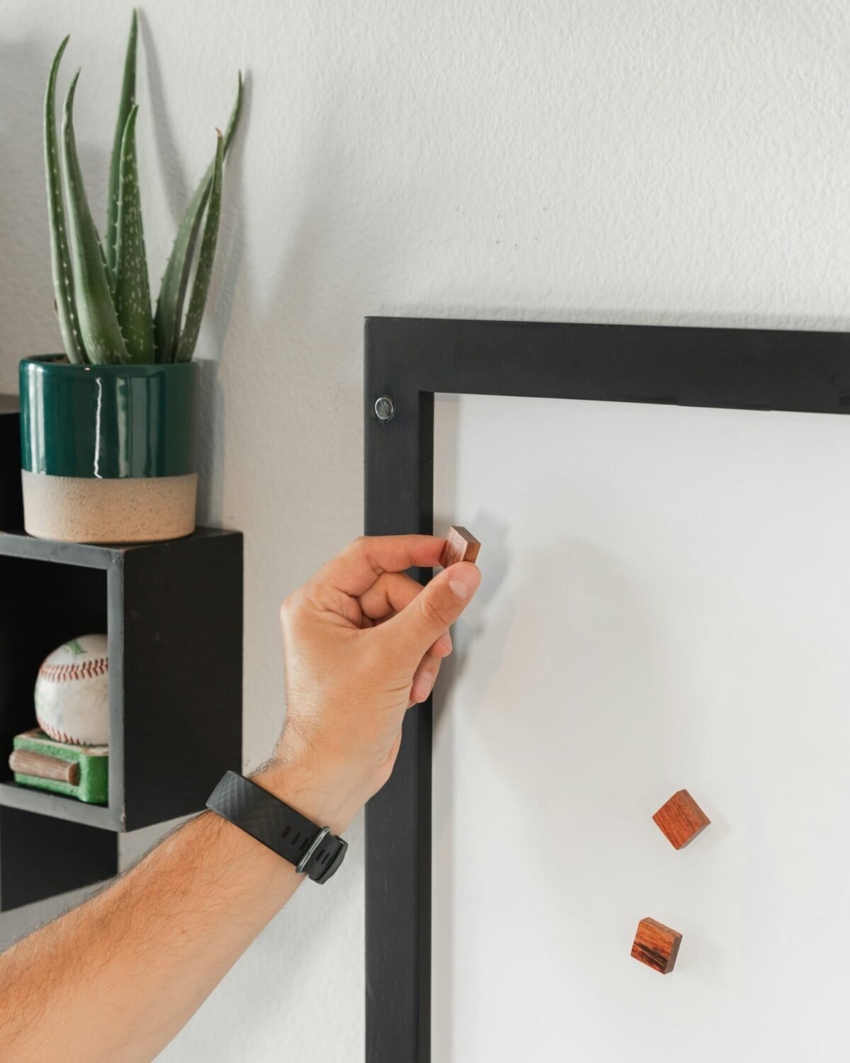 Close-up of a minimalist smart thermostat and light switch blending seamlessly with wall design in matching brushed metal finish