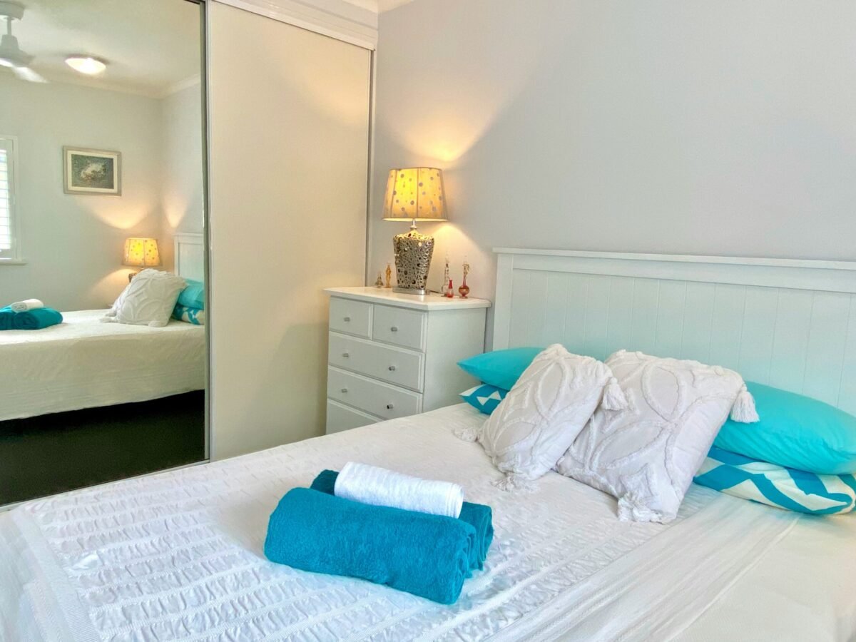 Flat lay of smart bedroom essentials including a smart bulb, smart speaker, smart thermostat, and under-mattress sleep tracker arranged on linen