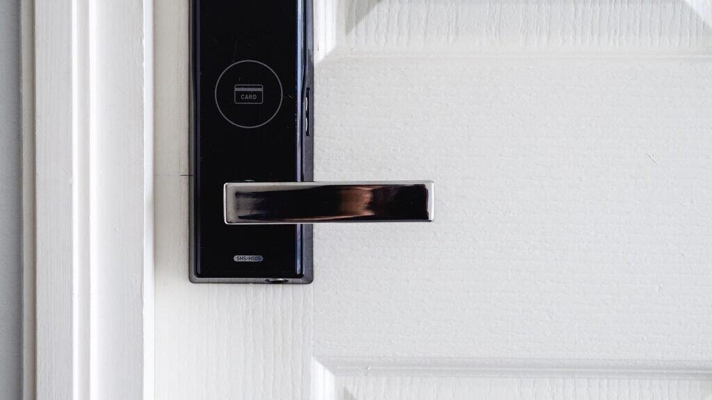 Modern front door with sleek keypad smart lock and video doorbell, stylish entryway with potted plant