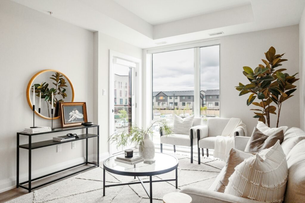 Minimalist apartment living room with clean lines, neutral decor, and automated shades at windows creating a peaceful, uncluttered space