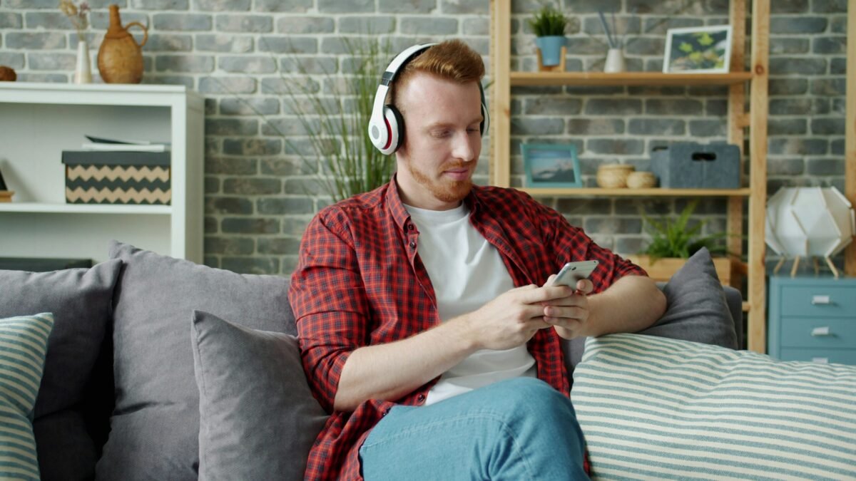 Person relaxing on comfortable couch using smartphone to control music in their smart home