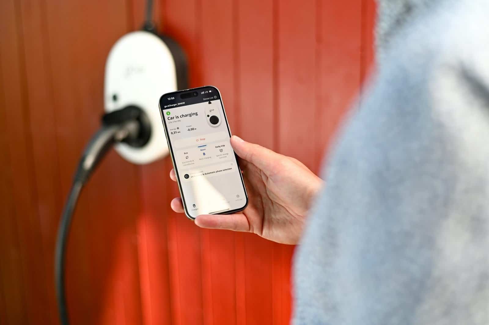 Person using smartphone to control smart home charging device.