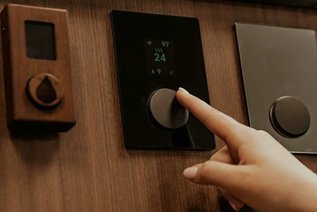 A close up of a digital smart thermostat mounted on a wall showing an energy-saving eco mode leaf icon.