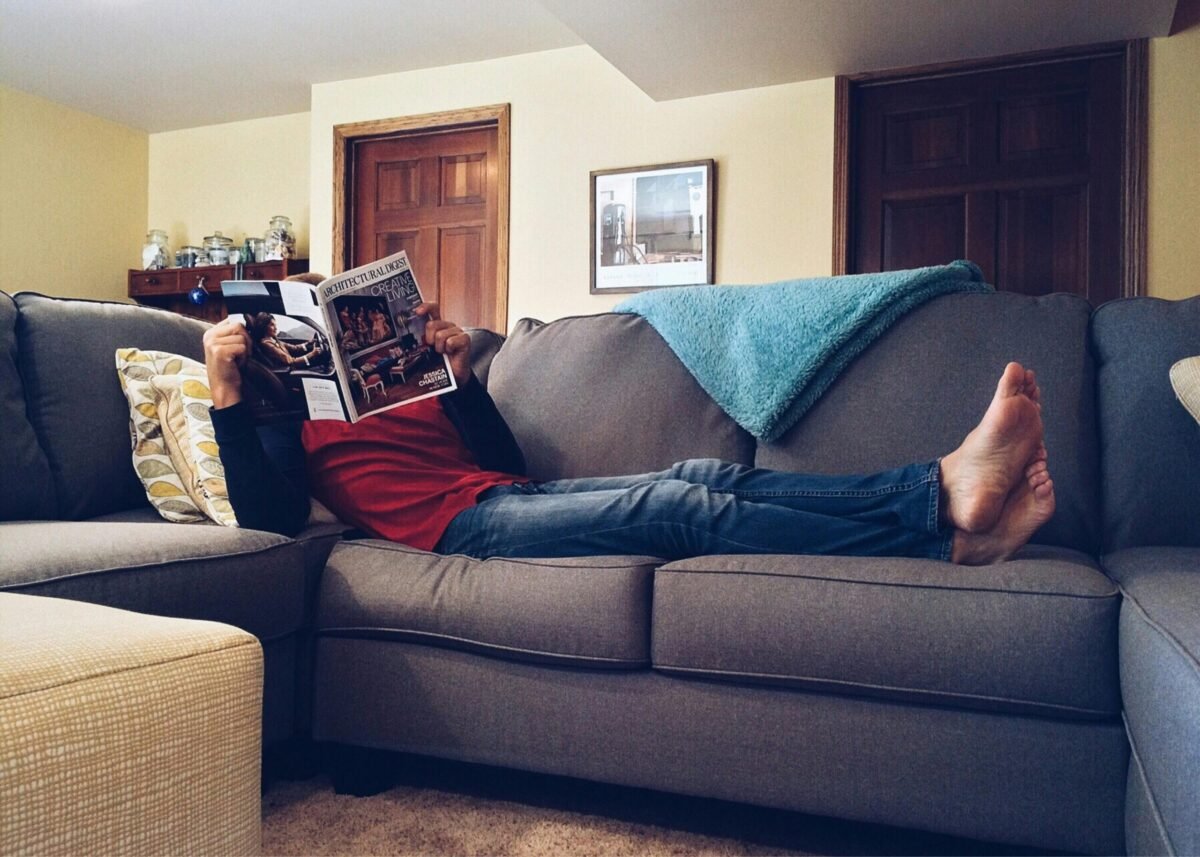 Person relaxing at home while smart home automation creates comfortable ambiance Caption: Well-designed routines handle repetitive tasks so you can focus on what matters